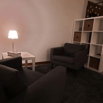 Przytulny gabinet psychoterapeutyczny z wygodnym fotelem i ciepłym oświetleniem.